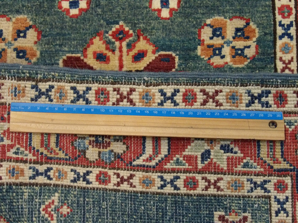 Green & Red Tribal Kazak rug in room setting