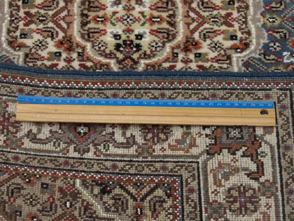 Beige and teal Tabriz rug in room setting