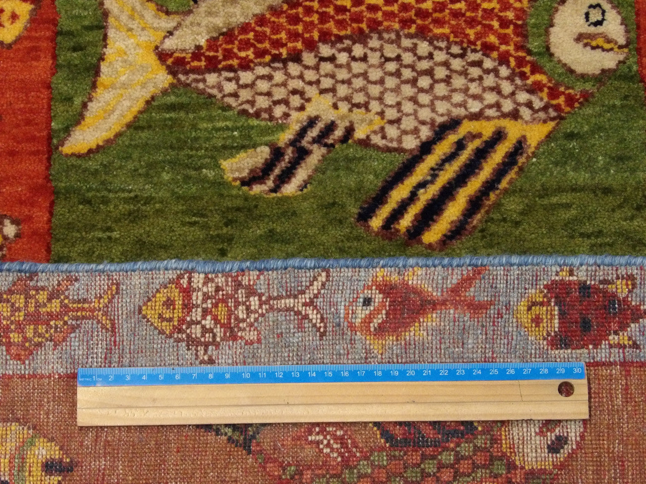 Blue and rust fish design rug in room setting