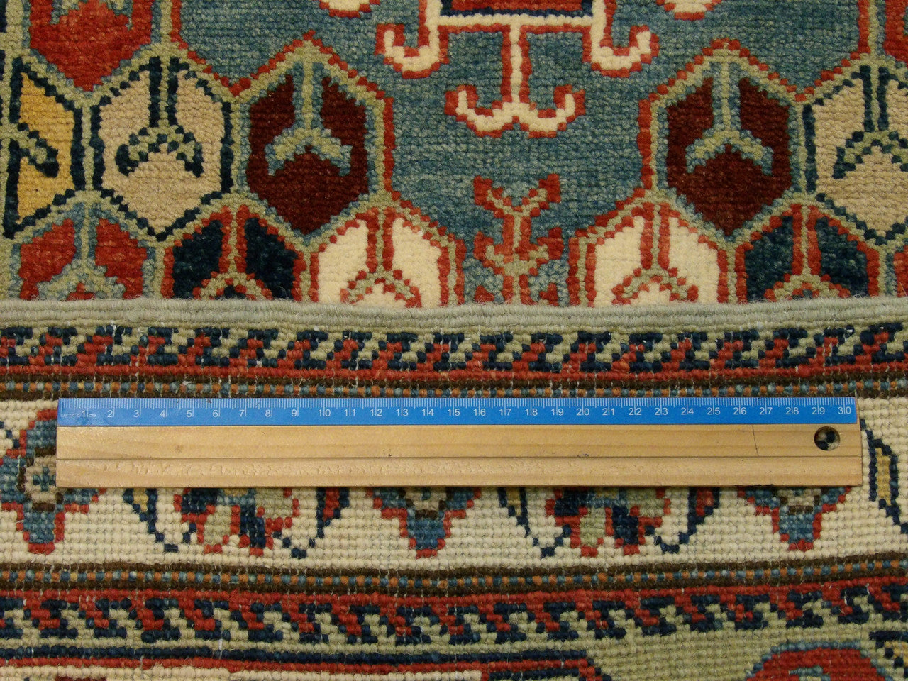 Green and ivory Kazak runner in hallway setting