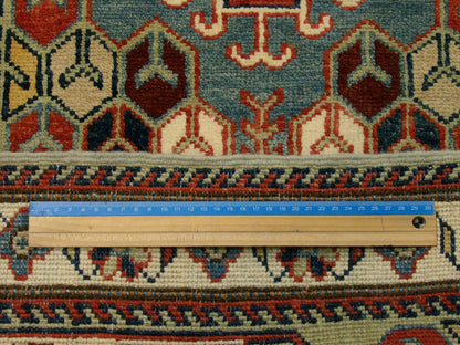 Green and ivory Kazak runner in hallway setting